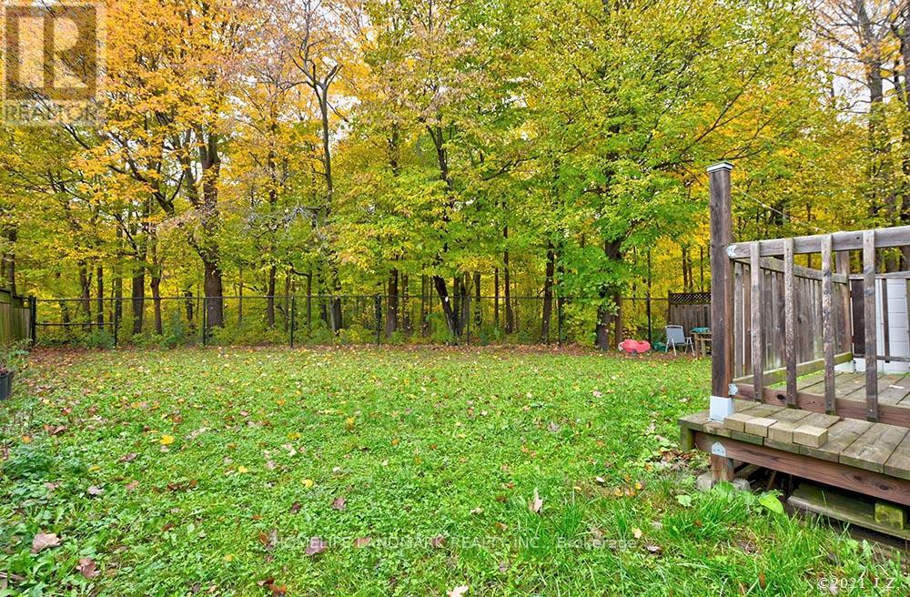 A backyard with a wooden deck and a grassy area with fallen leaves.