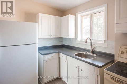A kitchen with white cabinets and a stainless steel sink.