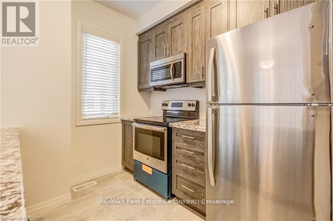 A kitchen with a stainless steel refrigerator and wooden cabinets.