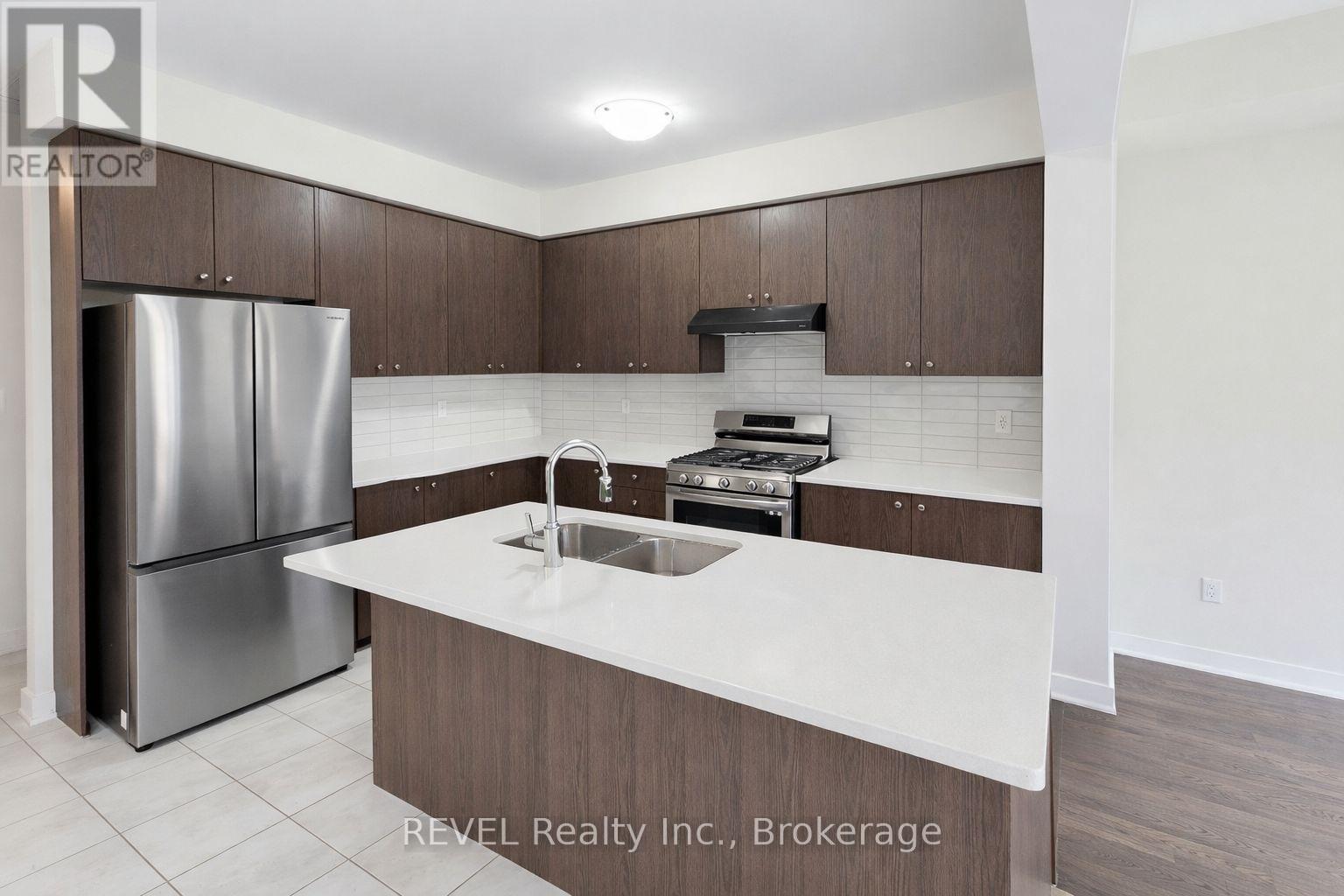 A kitchen with a refrigerator, sink, and stove top oven.