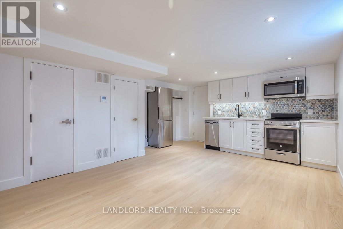 A spacious kitchen with white cabinets and a wooden floor.