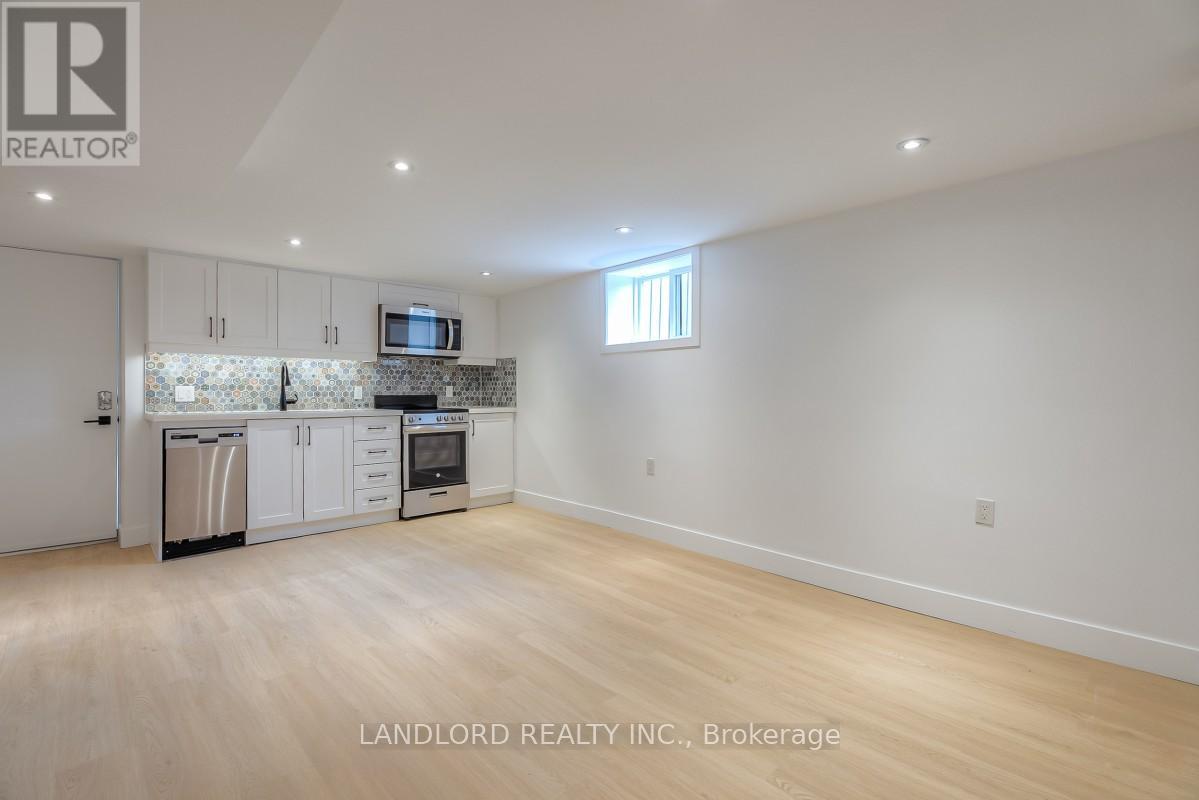 A spacious kitchen with white cabinets and a wooden floor.
