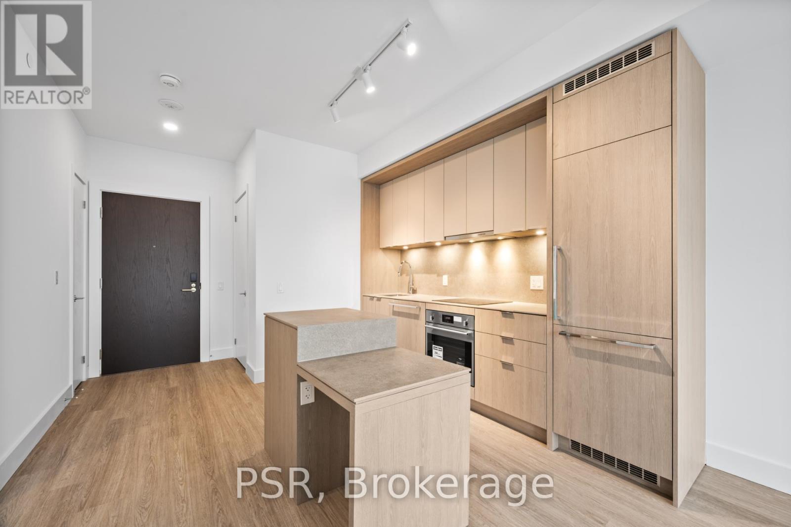 A modern kitchen with wooden cabinets and a black door.