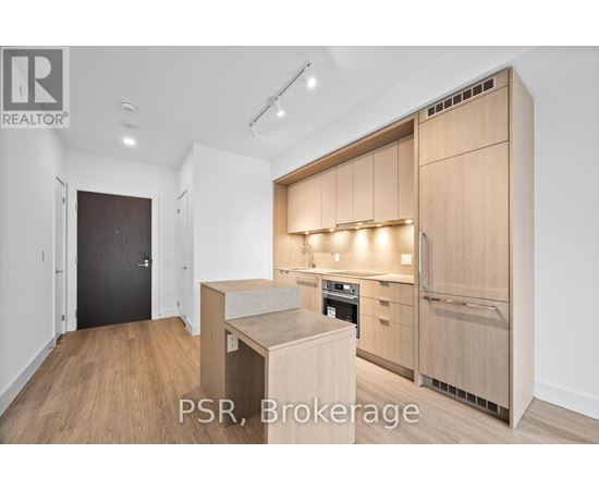 A modern kitchen with wooden cabinets and a black door.
