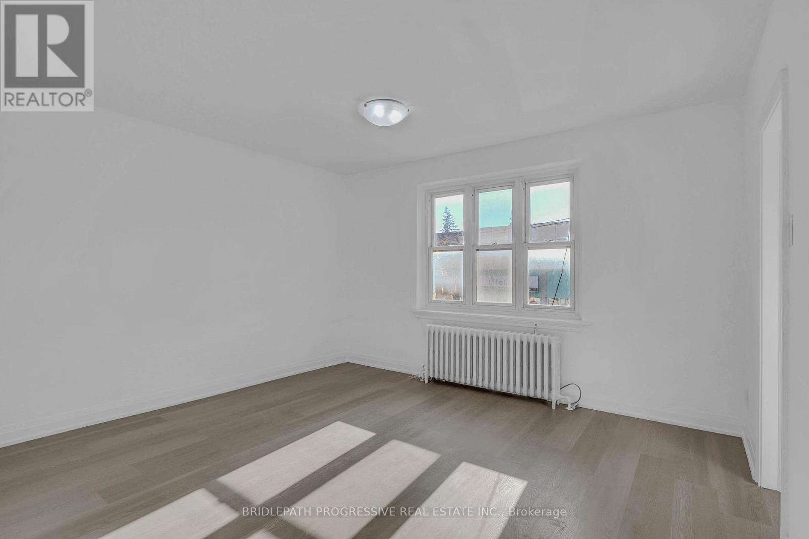A room with a window and a radiator on the floor.