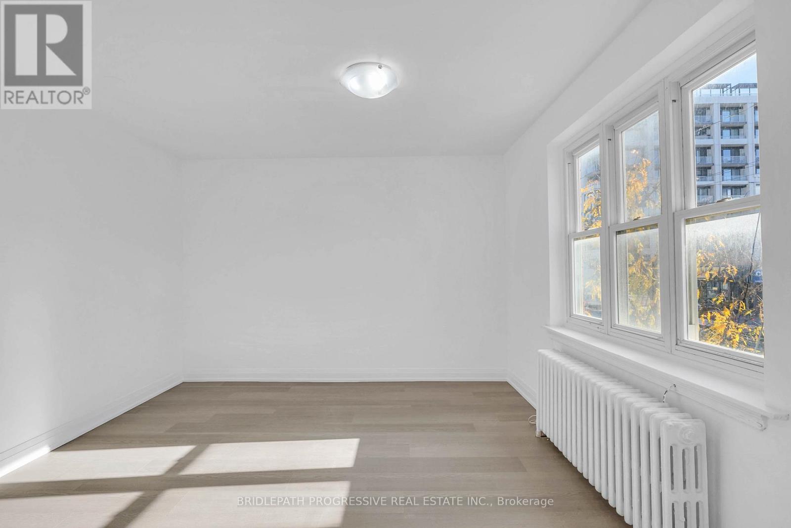 A white room with a window and a radiator on the wall.