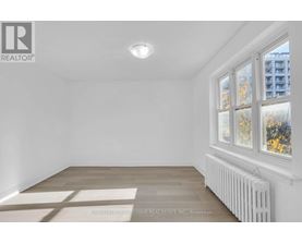 A white room with a window and a radiator on the wall.