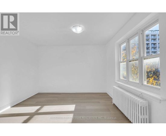 A white room with a window and a radiator on the wall.