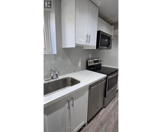 A kitchen with white cabinets and a black countertop.