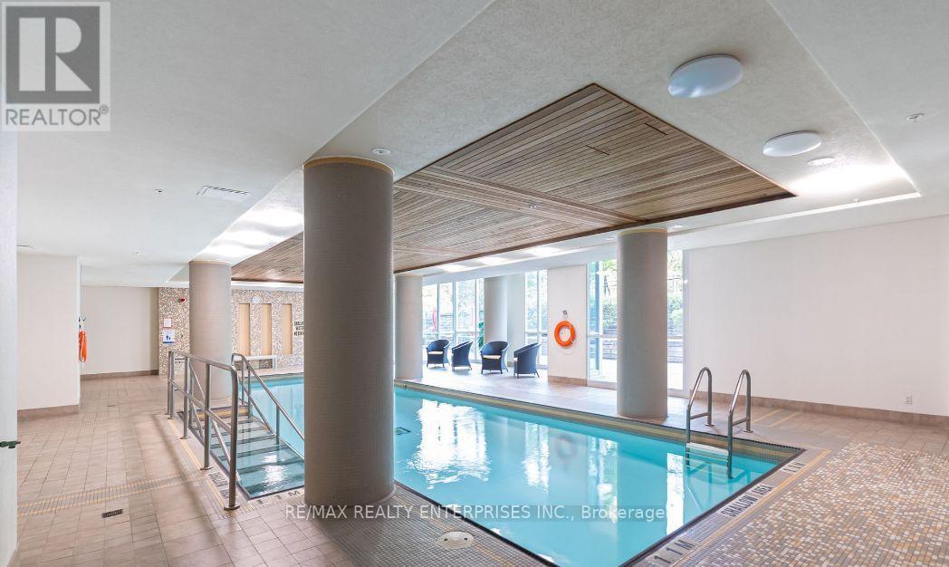 A large indoor swimming pool with a glass barrier and a wooden ceiling.