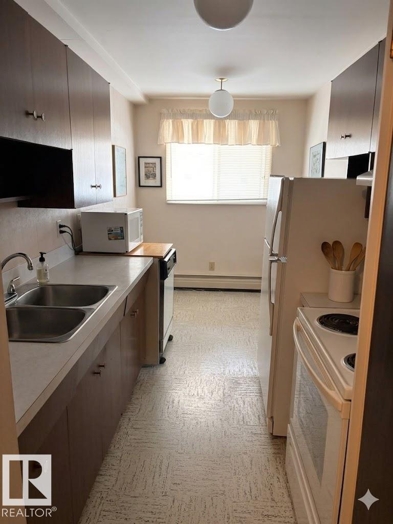A kitchen with a sink, stove, and refrigerator.
