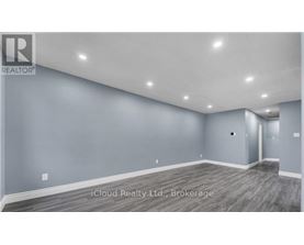 A spacious room with grey walls and wooden flooring.