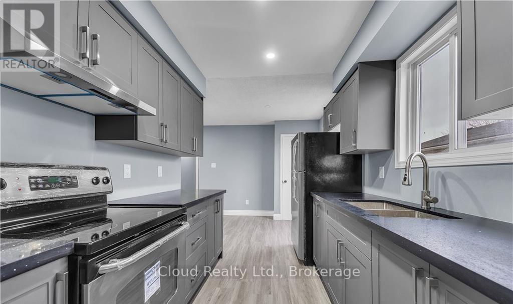A modern kitchen with stainless steel appliances and grey cabinets.