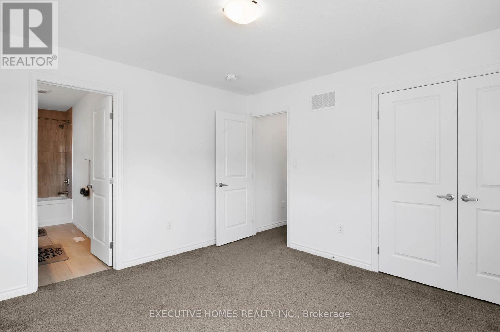 A white bedroom with a carpet floor and a ceiling light.