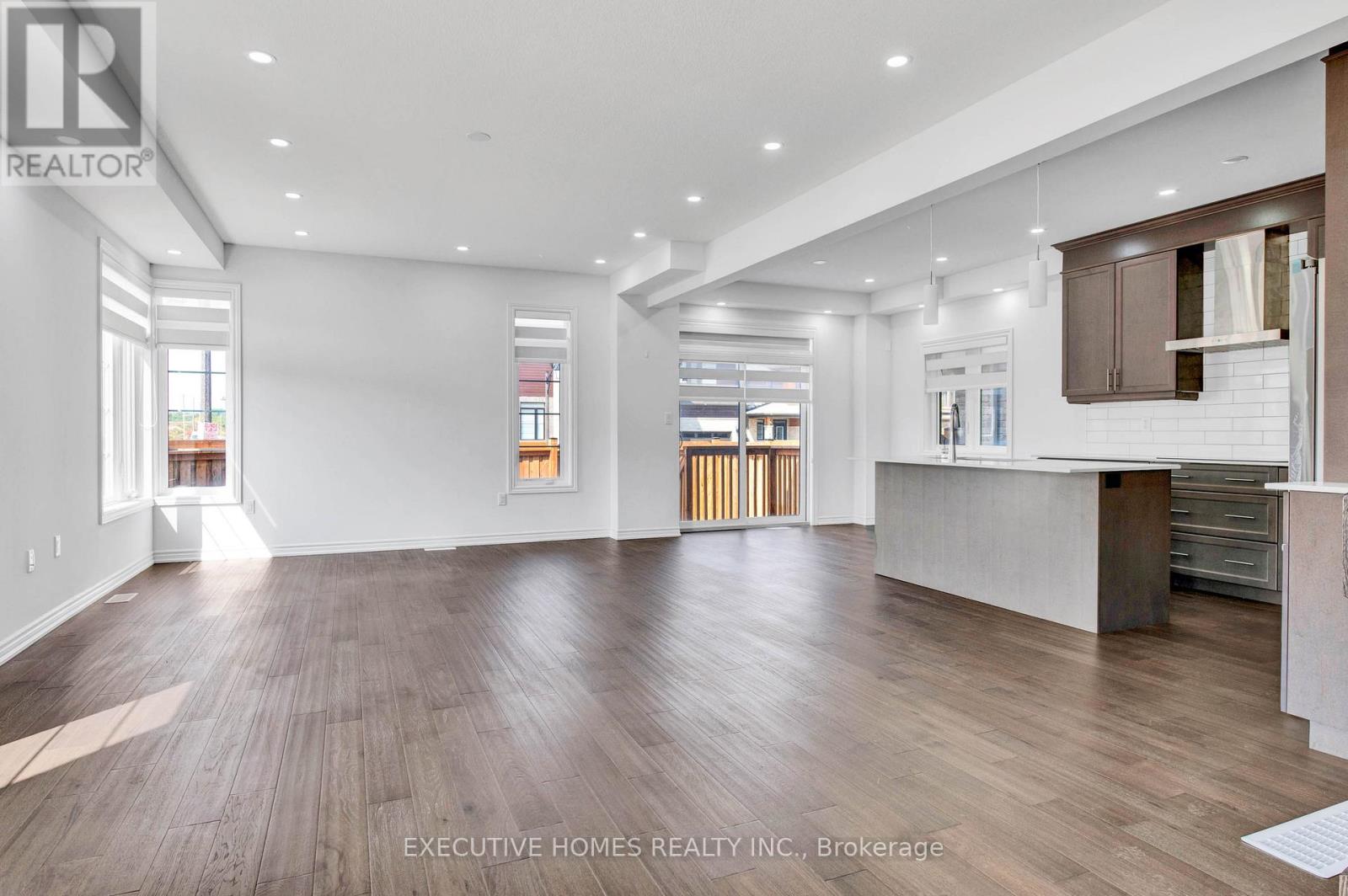 A spacious room with wooden flooring and white walls.