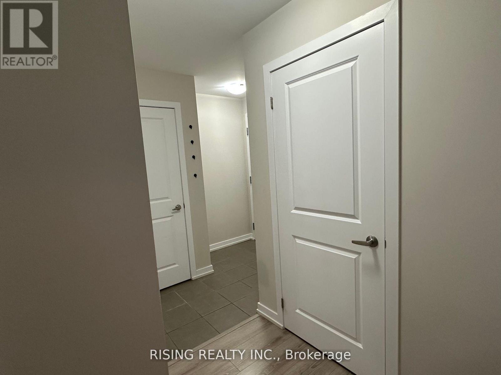 A hallway with two doors and a brokerage logo.