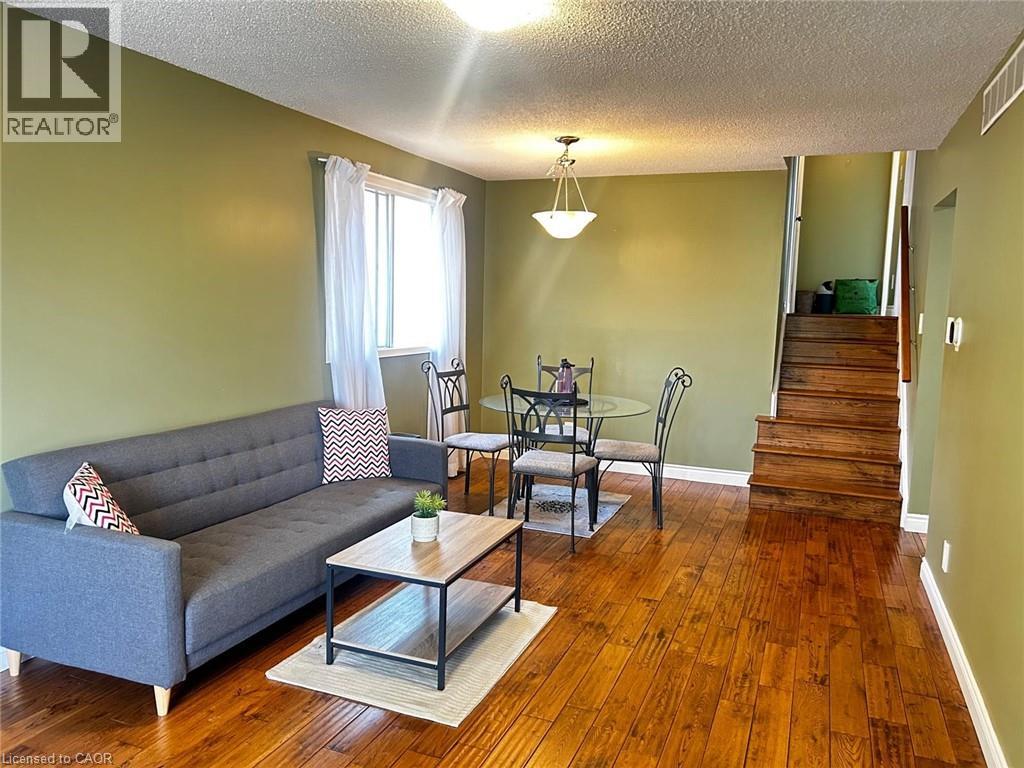 A living room with a grey couch, a glass coffee table, and a staircase.