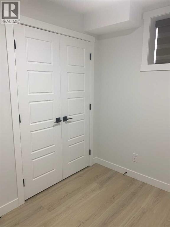 A white closet with a window and a wooden floor.