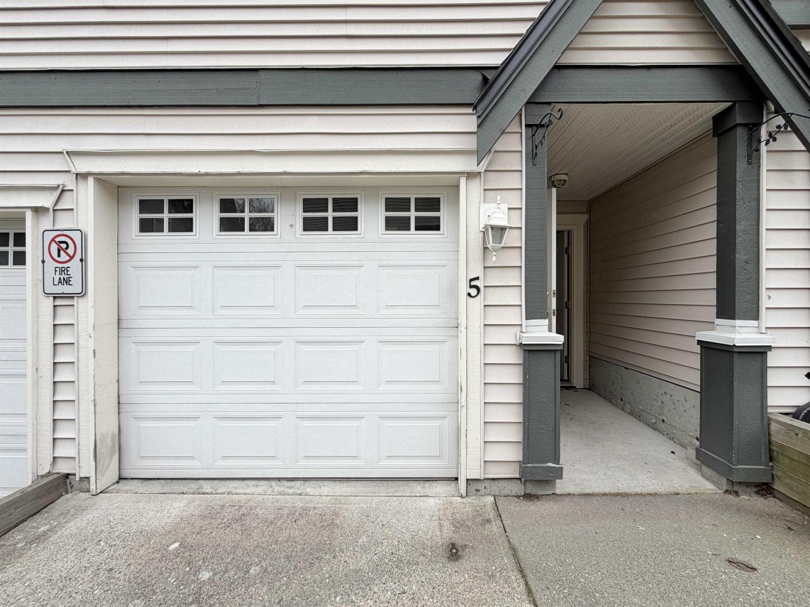 A white garage door with a no parking sign on the wall.