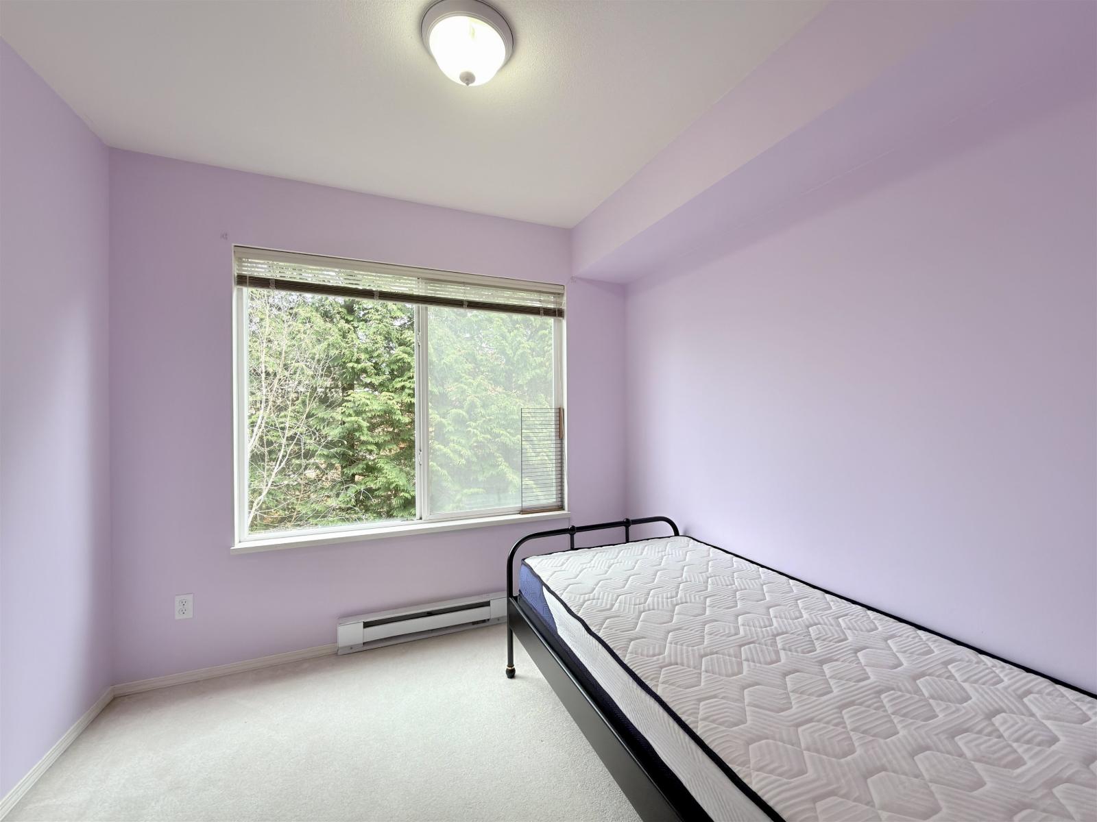 A bedroom with a bed, window, and air conditioner.