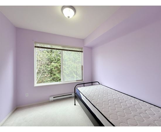 A bedroom with a bed, window, and air conditioner.