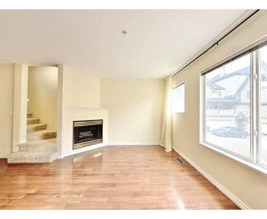 A living room with a fireplace and a staircase.