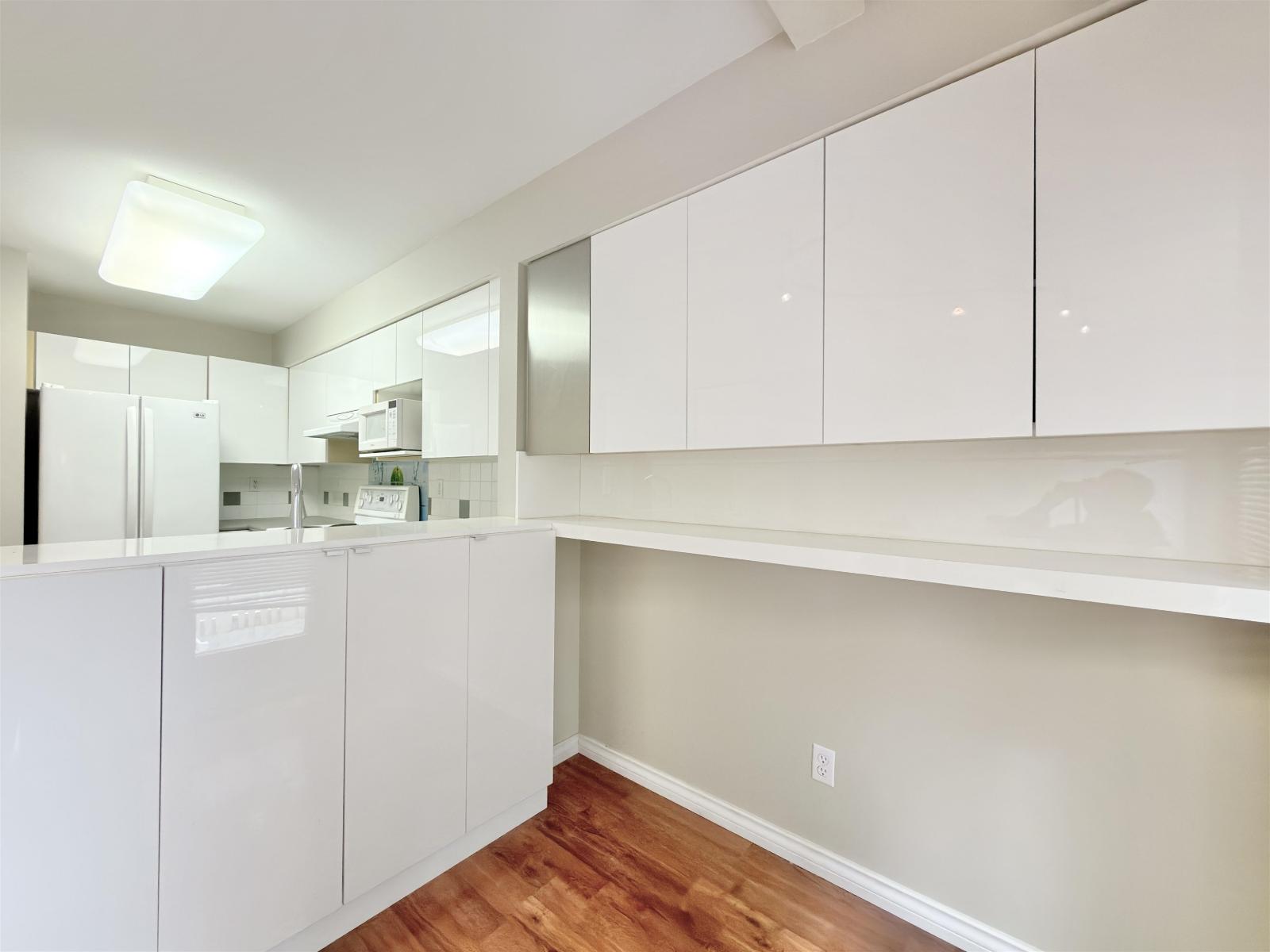 A kitchen with white cabinets and a wooden floor.