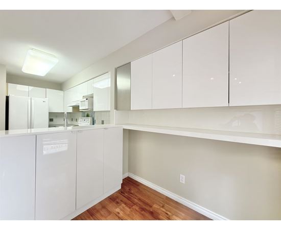 A kitchen with white cabinets and a wooden floor.