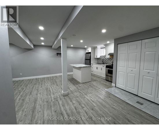 A spacious kitchen with white cabinets and a wooden floor.