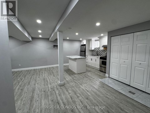 A spacious kitchen with white cabinets and a wooden floor.