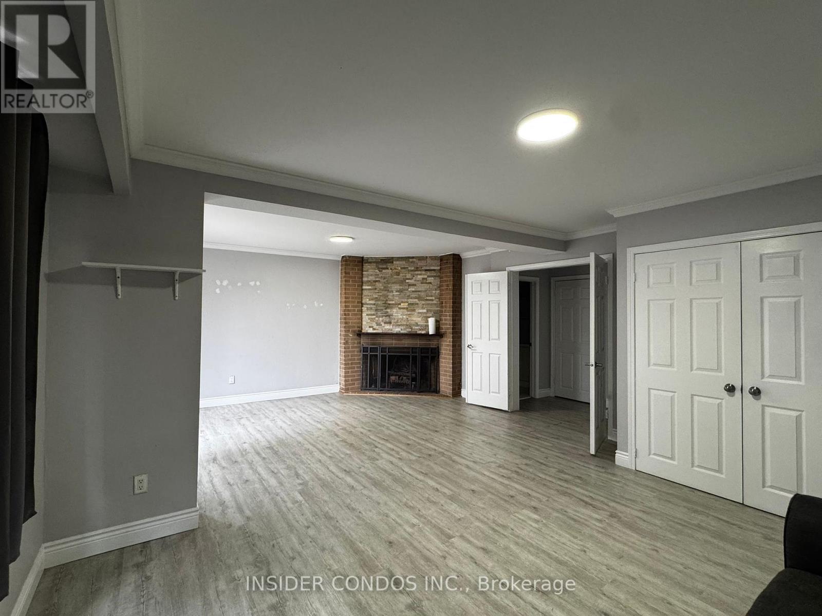 A spacious living room with a fireplace and wood flooring.