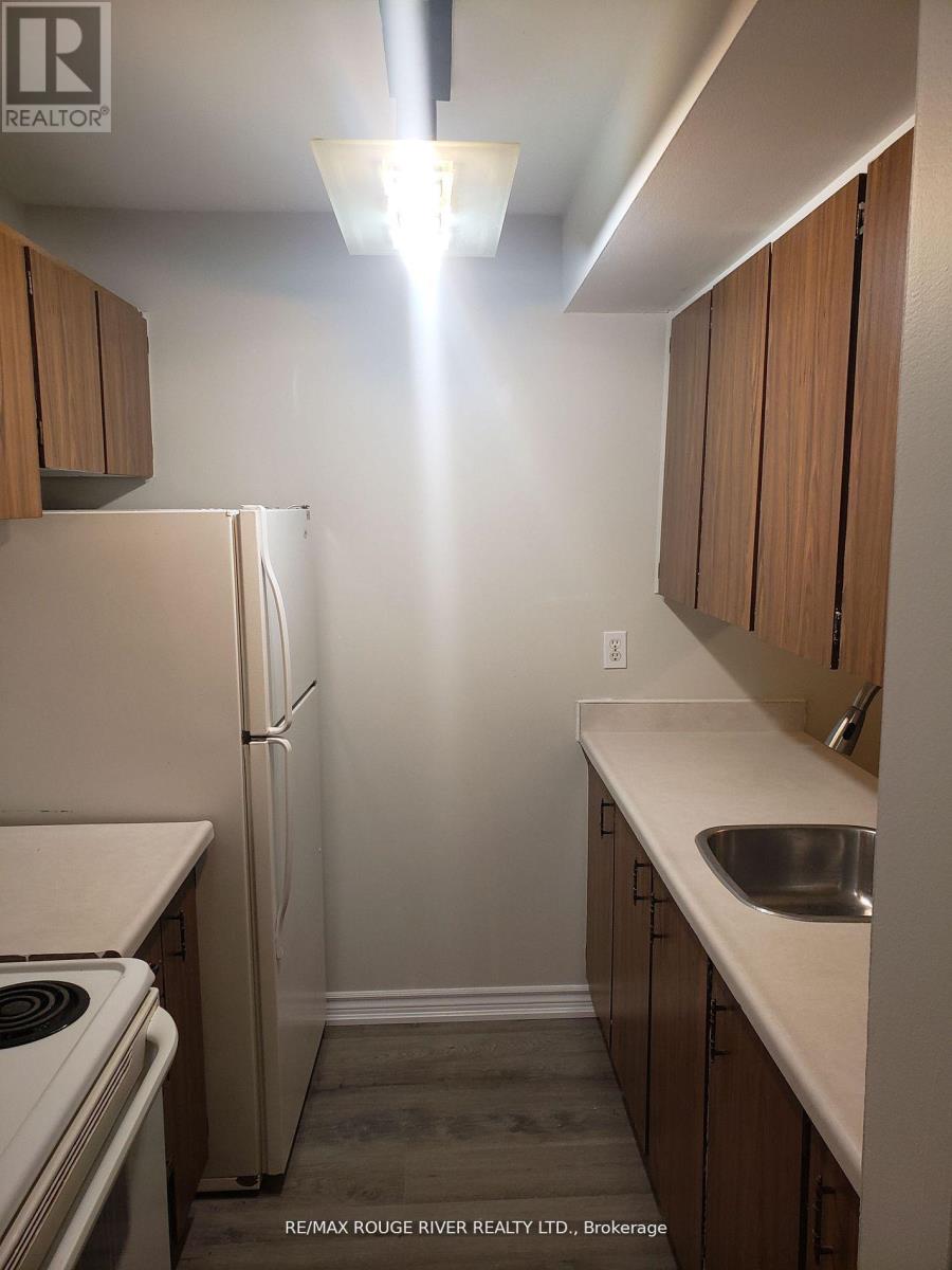 A kitchen with a refrigerator, sink, and stove.