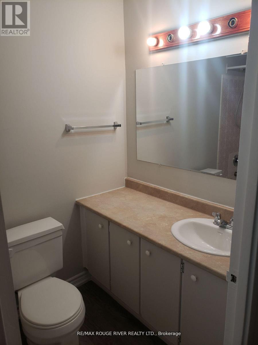 A bathroom with a toilet, sink, and mirror.