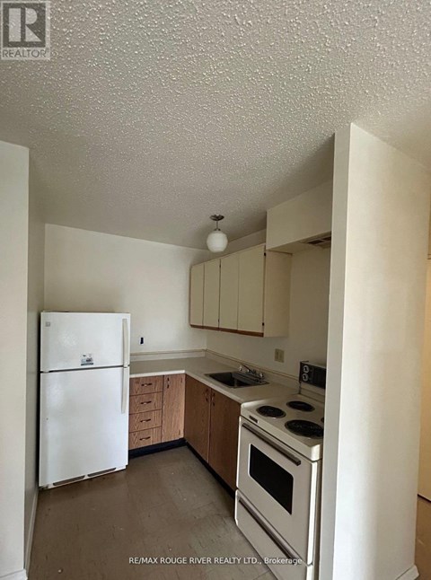 A white refrigerator is in a kitchen with wooden cabinets.