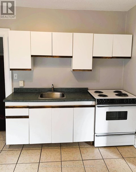 A kitchen with white cabinets and a black counter top.