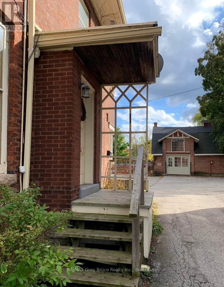 A wooden porch with a brick wall and a white door.