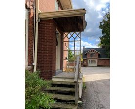 A wooden porch with a brick wall and a white door.