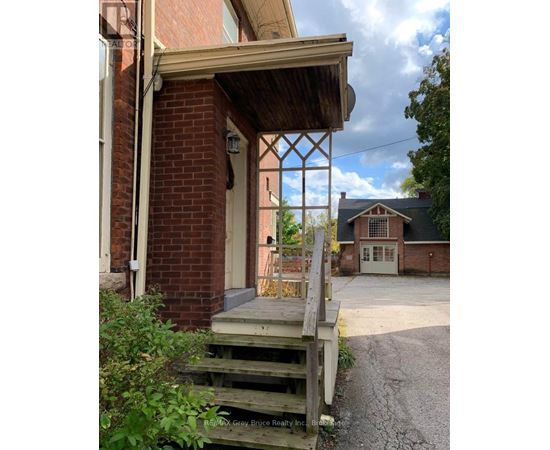 A wooden porch with a brick wall and a white door.