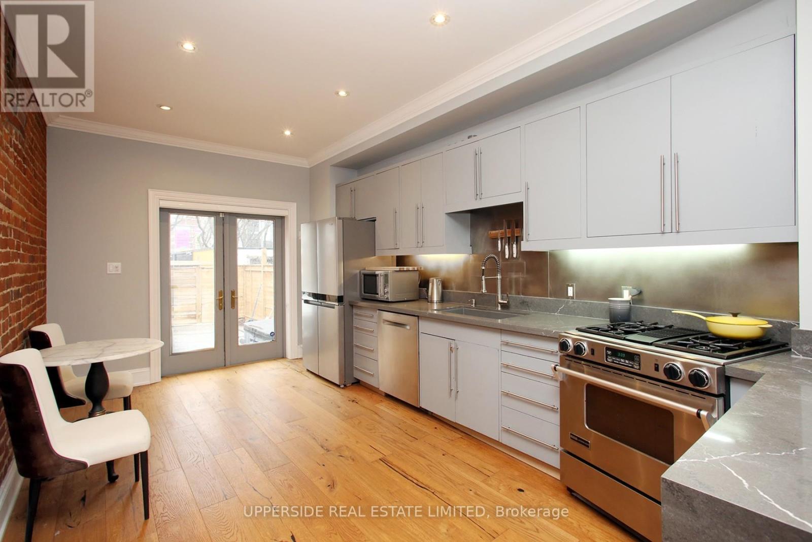 A kitchen with white cabinets and a brick wall.
