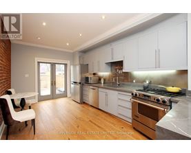 A kitchen with white cabinets and a brick wall.