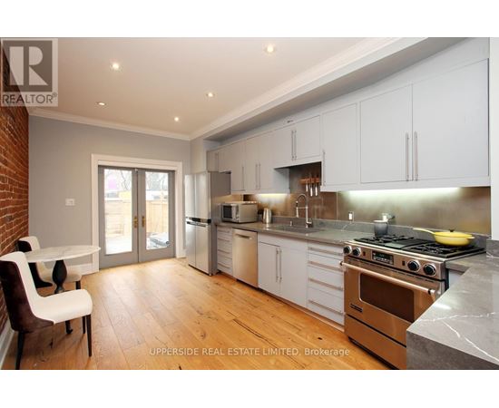 A kitchen with white cabinets and a brick wall.