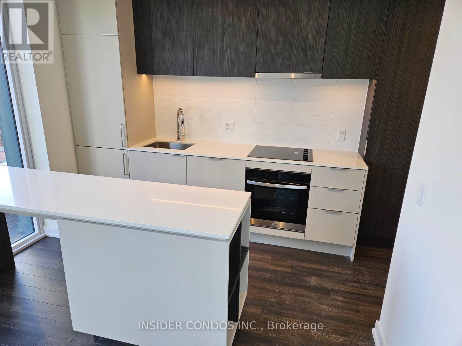 A modern kitchen with white countertops and dark wood cabinets.