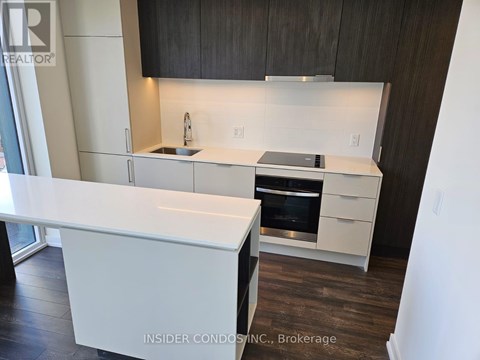 A modern kitchen with white countertops and dark wood cabinets.