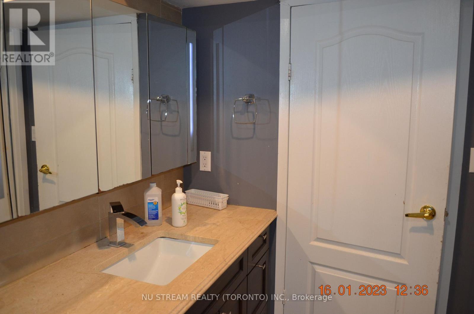 A bathroom with a sink, mirror, and cabinets.