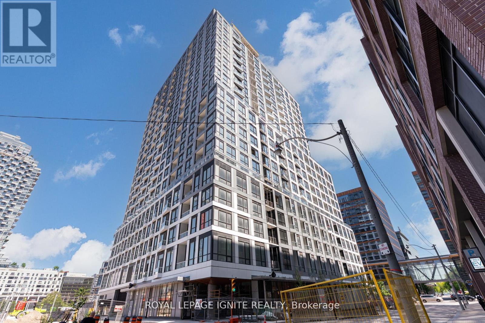 A tall building with a glass facade stands in the foreground of a city street.