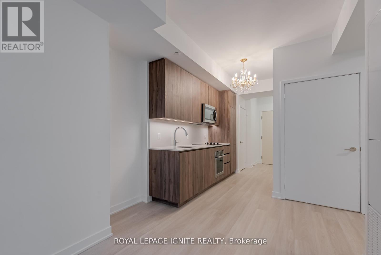 A well-lit kitchen with wooden cabinets and a white countertop.