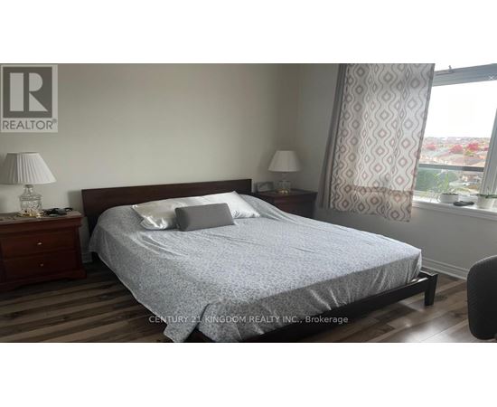 A bedroom with a bed, nightstands, and a window.