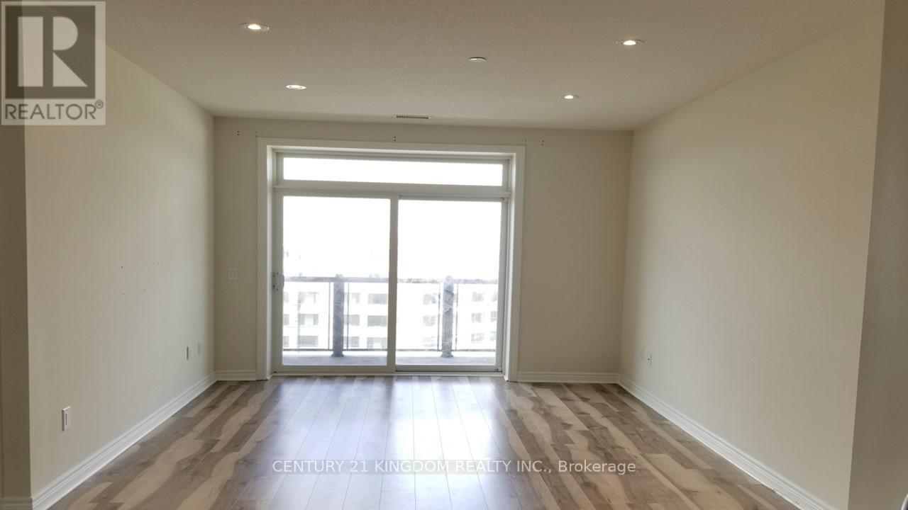 A spacious room with a large window and wooden flooring.