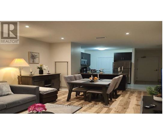 A well-lit living room with a grey sofa, a wooden coffee table, and a dining table set for two.