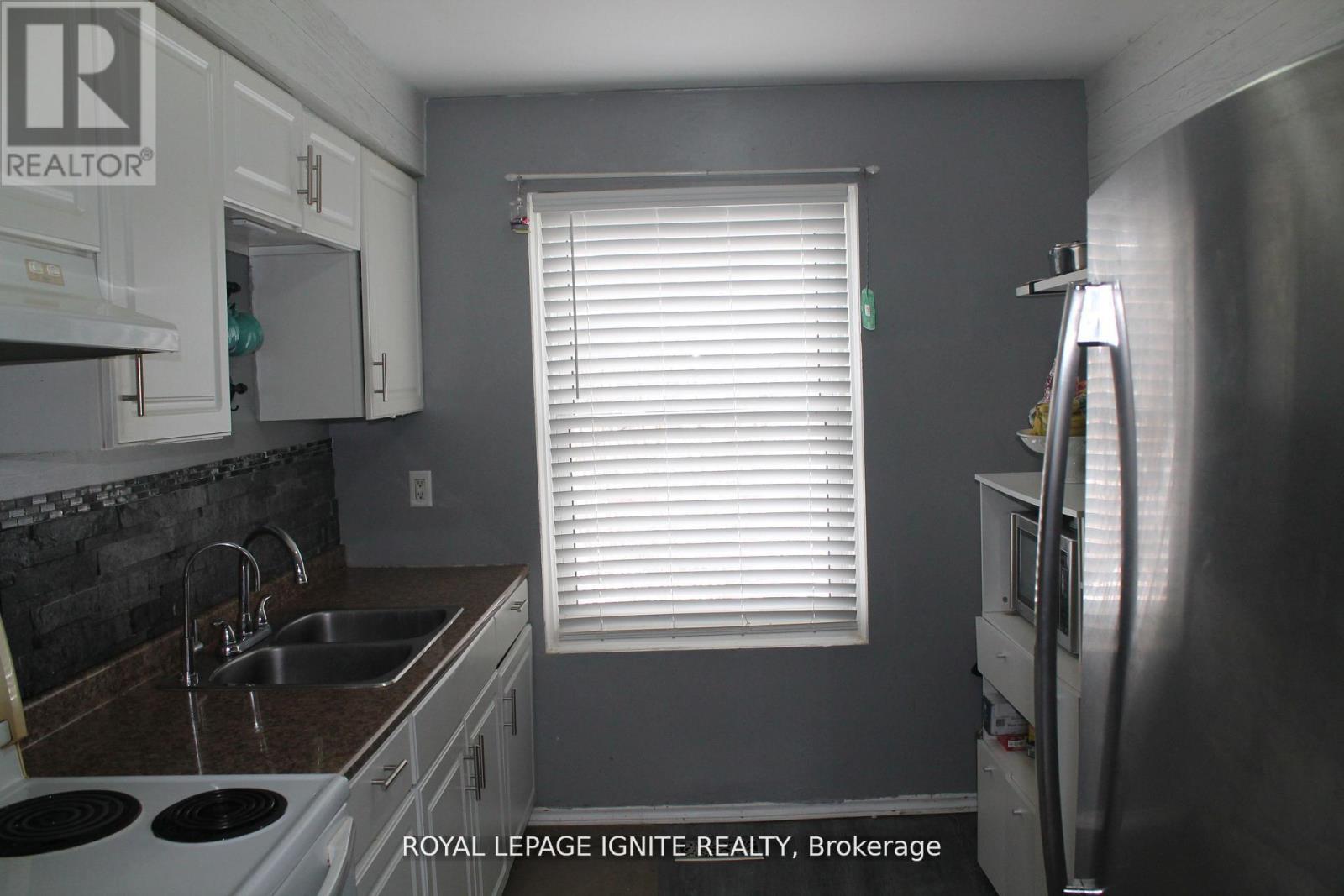 A kitchen with a stove top oven, sink, and refrigerator.